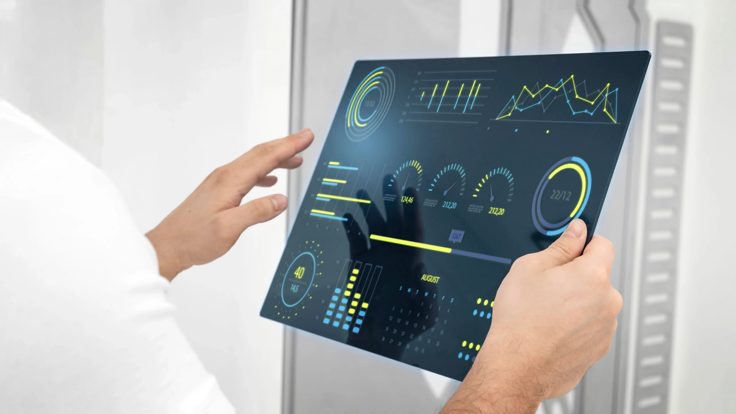 Close-up of a person holding a futuristic transparent touchscreen displaying digital dashboards, charts, and performance metrics.